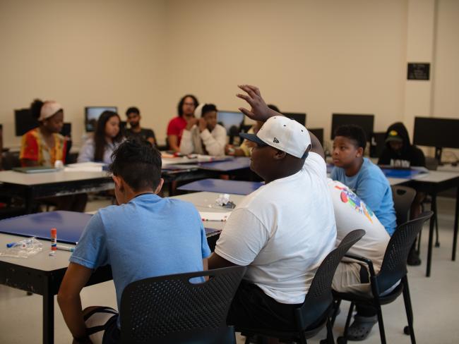 Young student raising his hand in a full classroom