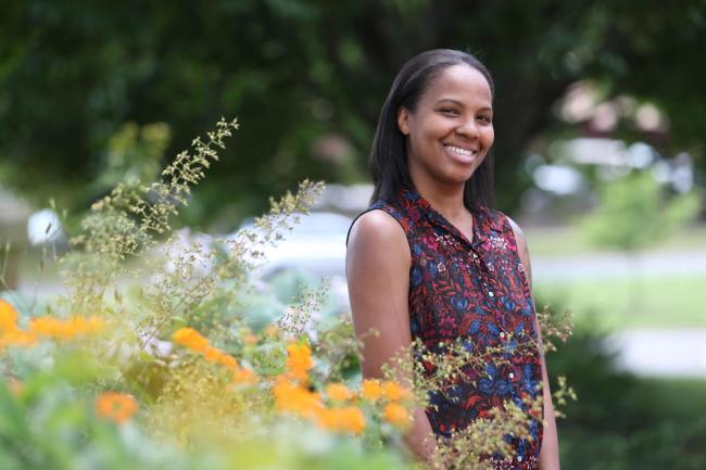 Siri Russell poses behind a beautiful array of flowers outdoors. 